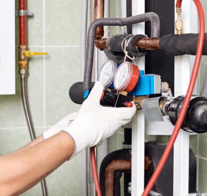 Maintenance engineer checking technical data of heating system equipment in a boiler room - Toms Plumber
