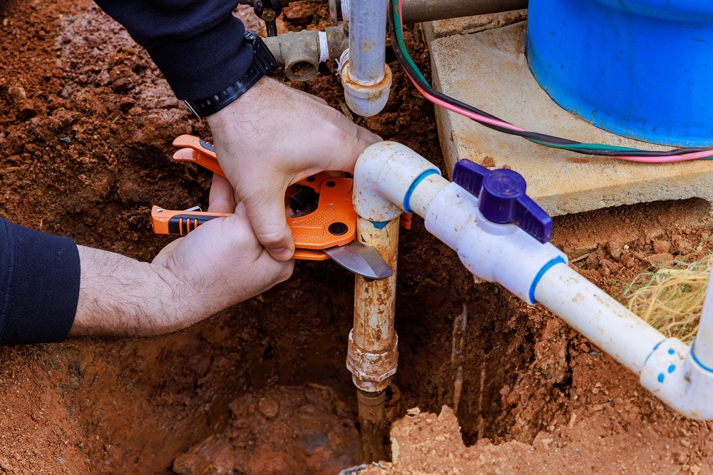 Cutting plastic PVC pipe with special pair of scissors by plumber