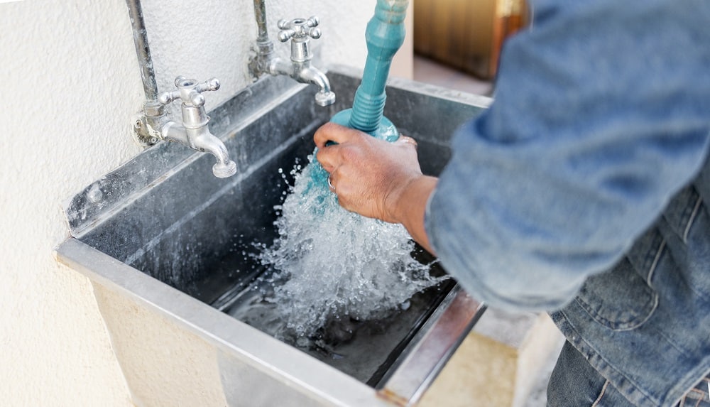 Plumber, water and man with plunger for kitchen sink, maintenance and repairs, blockage or cleaning.