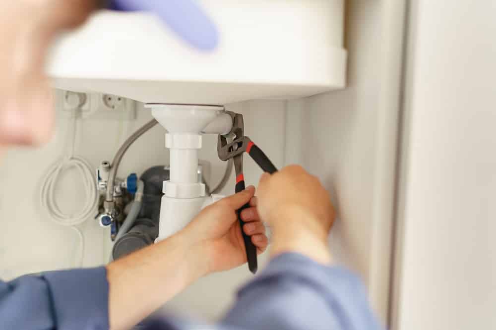 Close up of handyman installs a siphon pipe on the kitchen sink. High quality photo